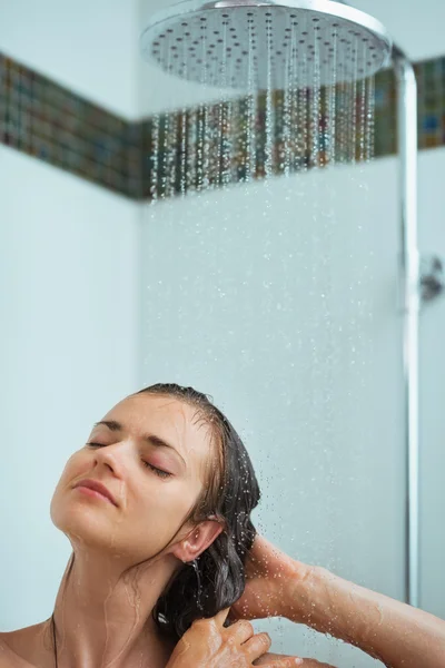 Relaxed woman taking shower under water jet