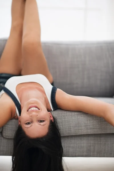 Happy young woman laying upside down on couch