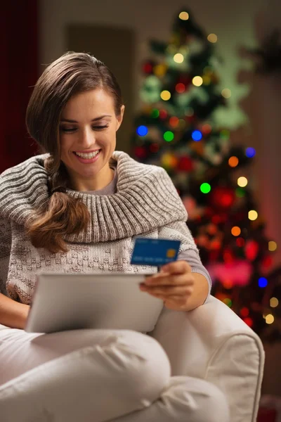 Happy woman with tablet PC and credit card in front of Christmas