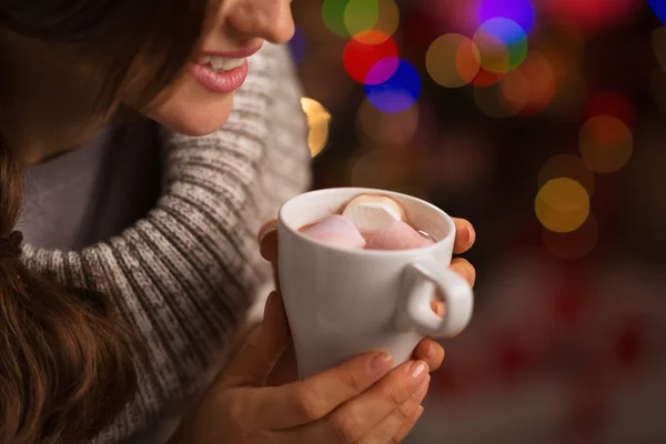 Closeup on hot chocolate with marshmallows in hand of happy woma