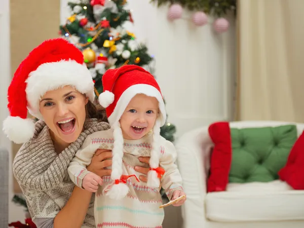 Portrait of mom and eat smeared baby girl in Christmas hats near