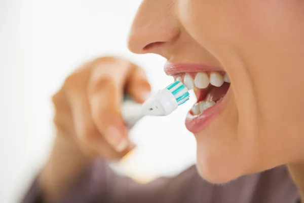 Closeup on happy young woman brushing teeth