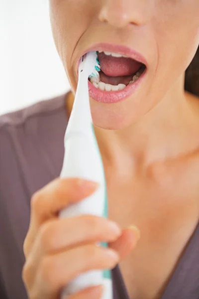 Closeup on young woman brushing teeth