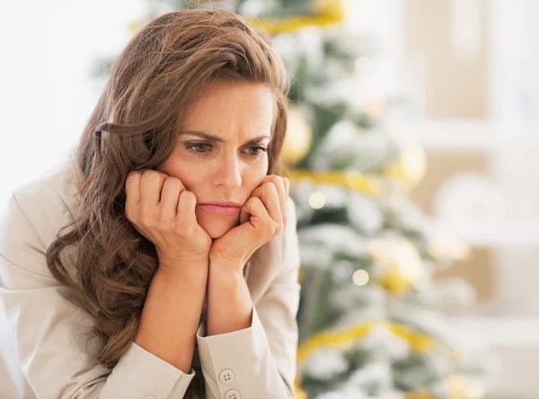 Portrait of frustrated young woman near christmas tree