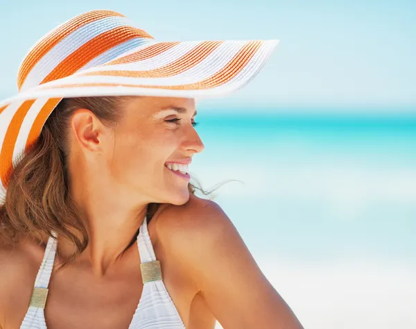 Portrait of happy young woman in swimsuit and beach hat looking