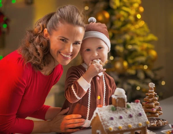 Mother and baby eating cookie in christmas decorated kitchen