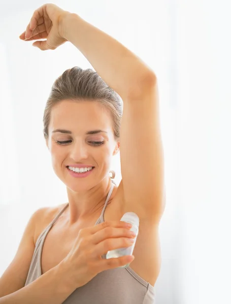 Happy young woman deodorant on underarm