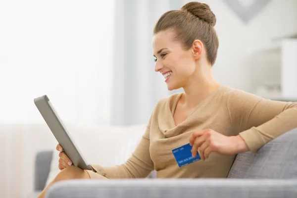 Happy woman with credit card using tablet pc
