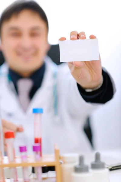 Focus on blank business card on hand of smiling doctor