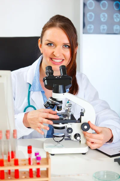 Smiling female medical doctor working with microscope in laborat