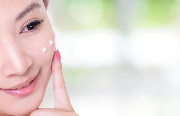 Half face of woman taking cream