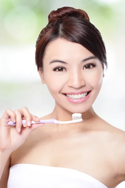 Smiling woman cleaning teeth with toothbrush