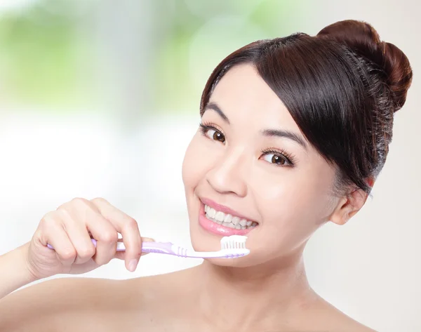 Smiling woman cleaning teeth with toothbrush