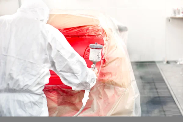 Automotive industry - car painter painting a red car