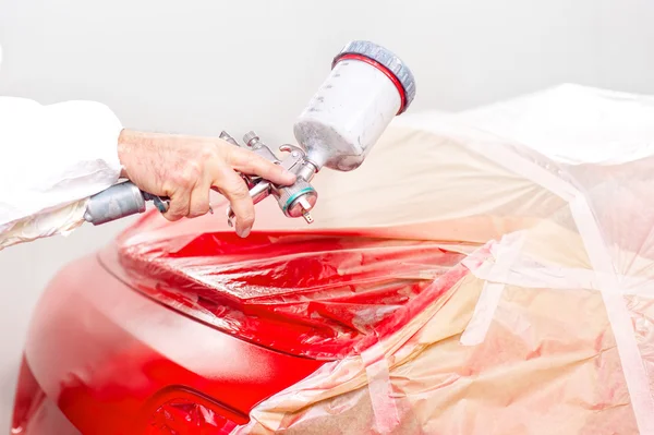 Auto engineer paiting a red paint on car in special booth
