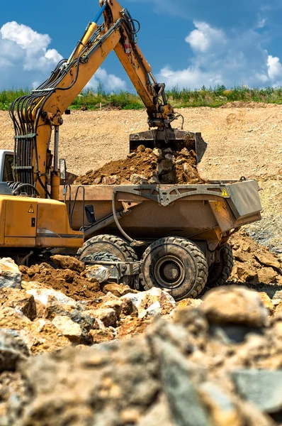 Excavator loading heavy duty dumper truck with rocks