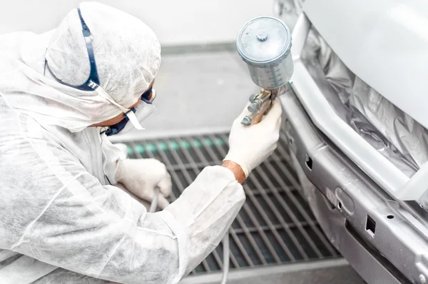 Auto mechanic engineer painting a grey car in a special booth