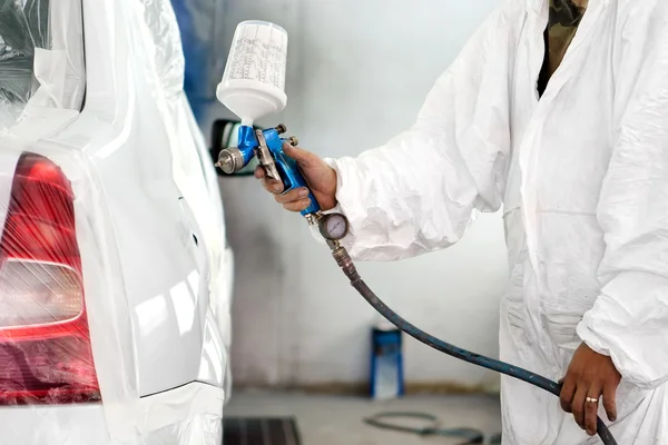 Automobile engineer spraying paint on a white car in a special