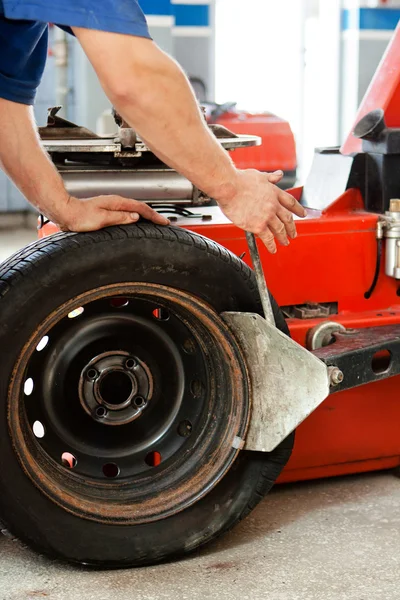 Auto mechanic manually changing the tyres on a classic rim