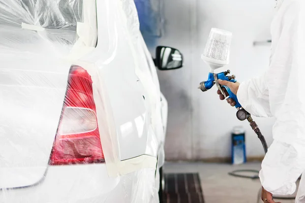 Automobile engineer spraying paint on a white car