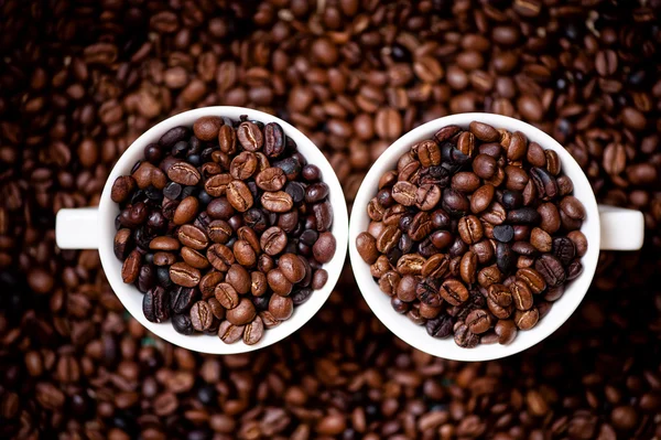 Detail of white cups of coffee filled with coffee beans, aromatic and fresh african coffee
