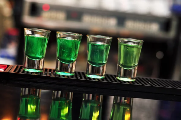 Blue and green drink in shot glasses standing on the counter