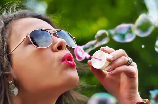 Close-up of sexy female blowing soap bubbles in park
