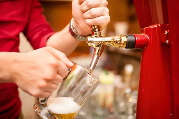 Bartender pouring beer draft in pub, bar or nightclub