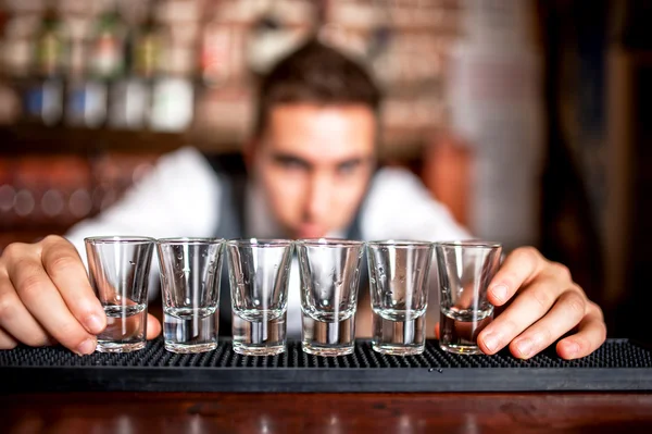 Bartender preparing and lining shot glasses for alcoholic drinks