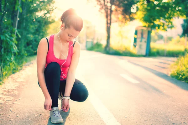 Woman running workout on spring sunny sunset. Fitness girl getting ready for jogging in city park