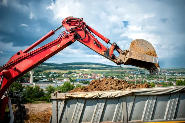 Close-up of industrial excavator loading a dumper truck with soil and earth from construction site