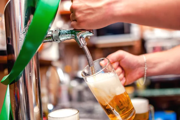 Close-up of barman brewing a draft beer at pub. Bartender pouring beer in a mug