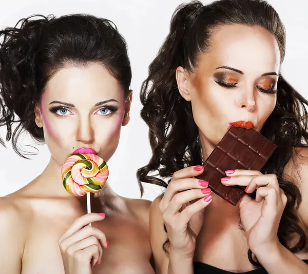 Two Beautiful Woman with Sweet - Lollipop and Chocolate Bar. Pleasure