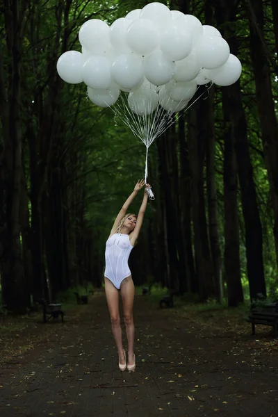 Fantasy. Nostalgic Svelte Woman with Air Balloons on Country Road