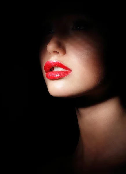 Darkness. Woman\'s Face with Sexy Red Lips in Spotlight and Shadows. Secrecy