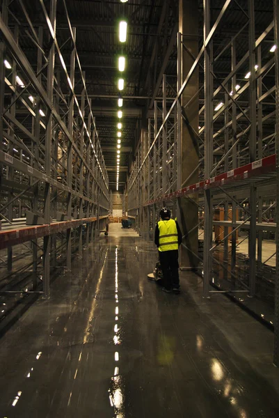 WORKER SCRUBBING FLOOR IN EMPTY WAREHOUSE