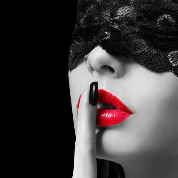 Hush. Sexy woman with finger on her red lips showing shush. Erotic girl with lace mask over black background. Black and white