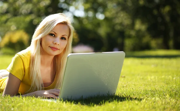 Blonde Girl with Laptop. Smiling Beautiful Woman Lying on Green