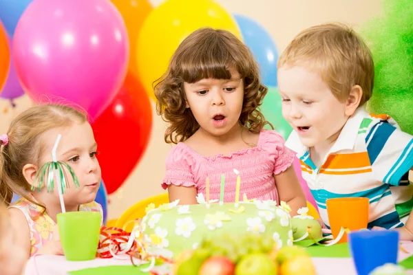 Kids celebrating birthday party and blowing candles on cake