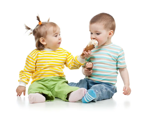 Babies girl and boy eating ice cream together in studio isolated
