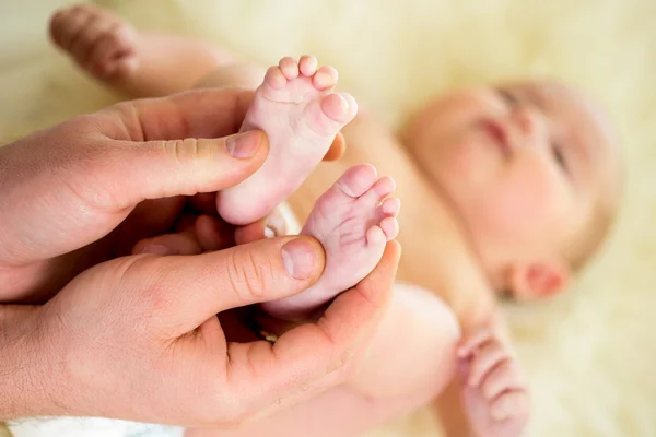 Father or doctor massaging small baby\'s foot