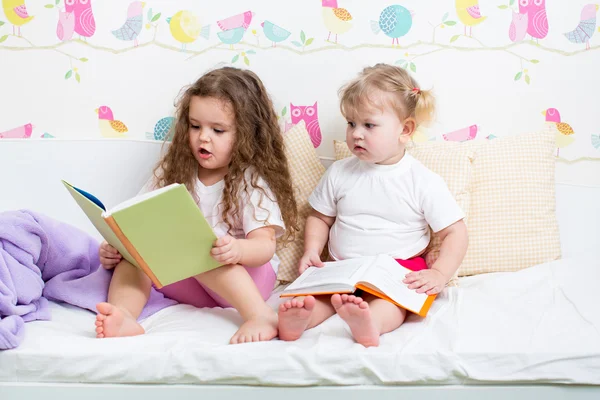 读一本书躺在<em>床</em>上的<em>孩子</em>们<em>姐妹</em> - 图库照片oks
