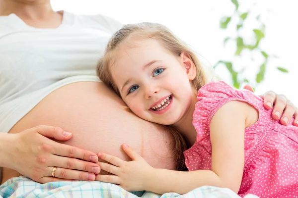 Happy kid girl hugging pregnant mother\'s belly