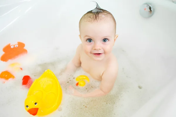 Smiling baby girl taking bath and playing with toys