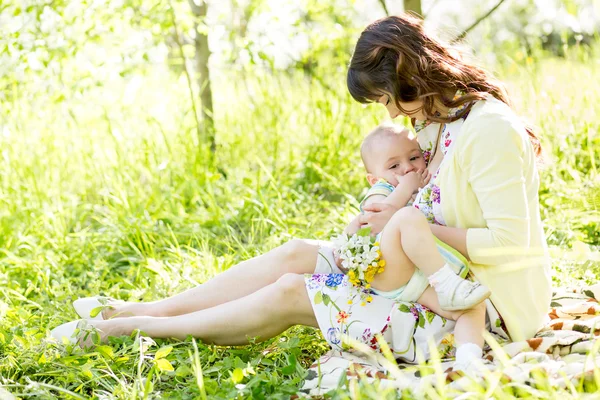 Young mother breast feeding her baby outdoors summertime