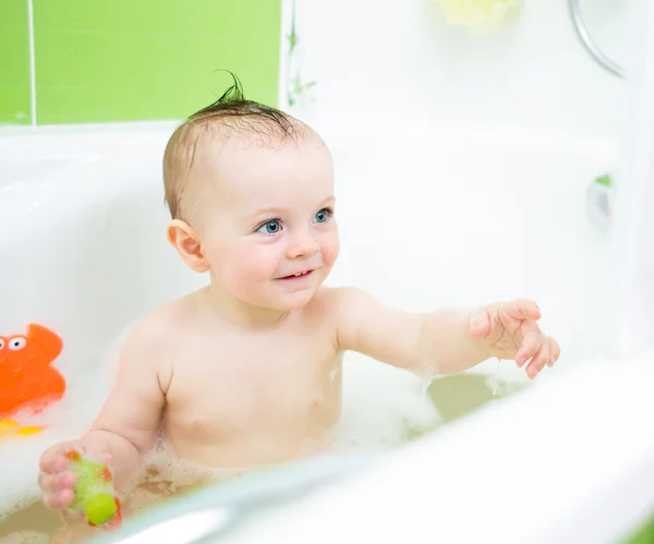 Smiling baby girl taking bath and playing with toys