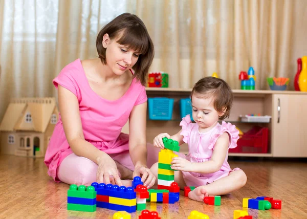 Mom and kid girl playing block toys at home