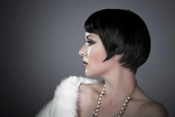 Gourgeos female brunette flapper profile wearing pearls and fur