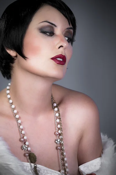 Gourgeos female brunette flapper wearing pearls and fur