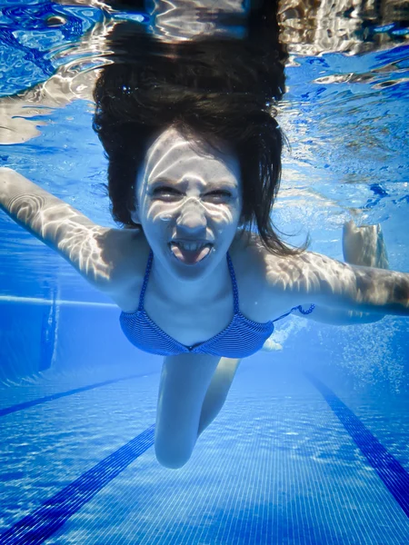Teenage swimming underwater in the pool with funny face